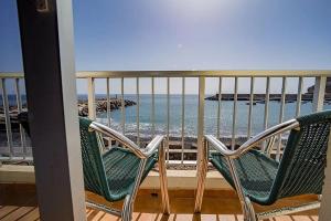 two chairs sitting on a balcony looking out at the ocean at Pensión La Gaviota in Playa de Santiago
