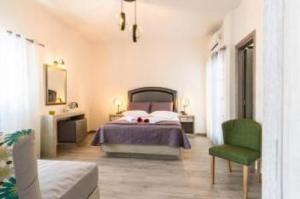ein Schlafzimmer mit einem Bett und einem grünen Stuhl in der Unterkunft Villa Kalamia Dolphin in Perissa