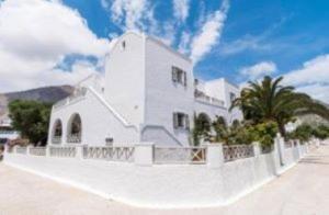 ein weißes Gebäude mit Zaun und Palmen in der Unterkunft Villa Kalamia Dolphin in Perissa