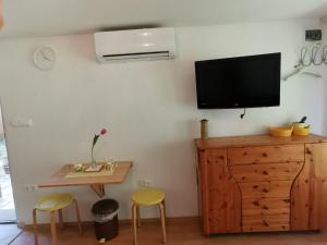 a room with a tv on a wall with a table and stools at Kaméleon Apartmanház EV töltéssel in Balatonszemes