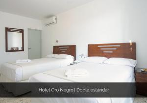 a bedroom with two beds and a mirror at Hotel Oro Negro in Talara