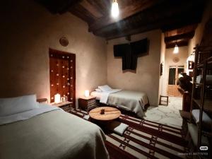 a bedroom with two beds and a table in it at Tanirt ecolodge in Siwa