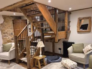 a living room with a wooden spiral staircase at The Old Mill Annexe in Jacobstowe