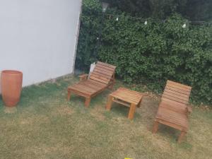two wooden chairs and a bench in a yard at Elu in Ingeniero Giagnoni +2 photos