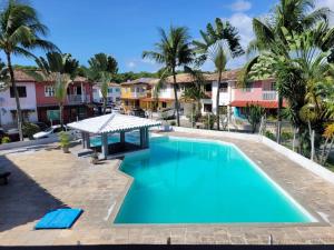 a swimming pool in a resort with palm trees at Casa maricota in Porto Seguro