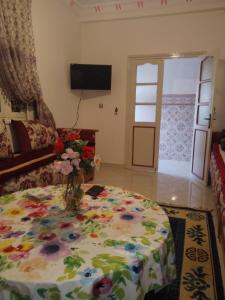 a room with a table with a vase of flowers on it at Maison de vacances zuine in Oujda
