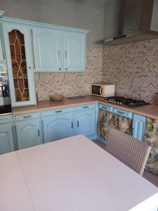 a kitchen with blue cabinets and a stove and a table at Maison Sol Air in Montazels