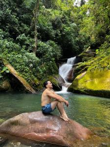 a man sitting on a rock in front of a waterfall at Stark house in Moyobamba