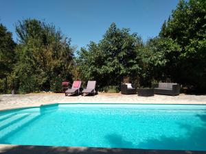 a swimming pool with two chairs and a beach at Les feuillets de la Buire in Monteux