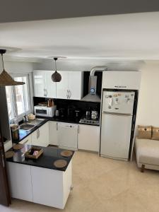 a kitchen with white cabinets and a refrigerator at Detached house with pool in Alaçatı in Çeşme