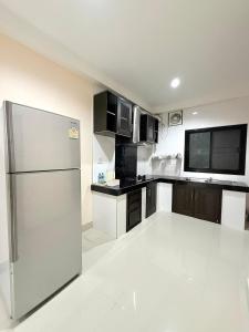 eine Küche mit Edelstahlkühlschrank und Flachbildfernseher in der Unterkunft THAM Ranong in Ranong + 15 Fotos