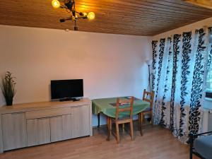 a living room with a table and a tv on a cabinet at Hostel Fantasy in Gröbenzell
