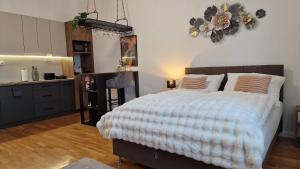 a bedroom with a large bed and a kitchen at Boudoir-Art Studio Apartment in Debrecen