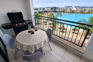 a balcony with a table and a grill and a view of the beach at Spectacular Lagoon Facing Apartment - The Blyde in Pretoria