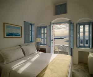 a bedroom with a bed and a view of the ocean at Aigialos Luxury Traditional Settlement in Fira +90 photos