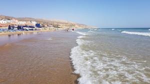 a beach with a bunch of people and the ocean at Appartement pieds dans l'eau Aghroud in Tamri
