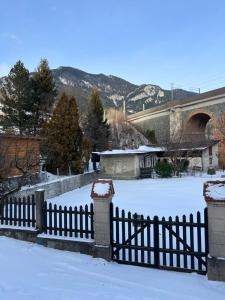 a fence covered in snow with a bridge in the background at Hotel Zemlinski in Payerbach