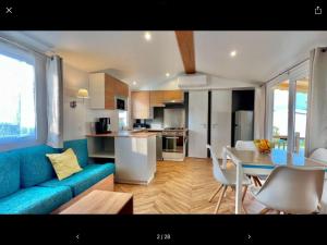a living room and kitchen with a blue couch and a table at Bien dans le sud in Fréjus