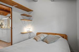 a white bedroom with a bed and a kitchen at 3000-Stege-Stejlepladsen-13 in Stege