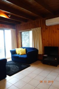 a living room with a blue couch and windows at Morella Farmstay in Cape Jervis
