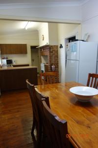 a kitchen with a wooden table with chairs and a white refrigerator at Morella Farmstay in Cape Jervis