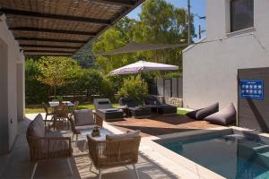 a patio with a pool and chairs and an umbrella at SEASCAPE VILLAS VASSILIKI - Beachfront villas in Vasiliki