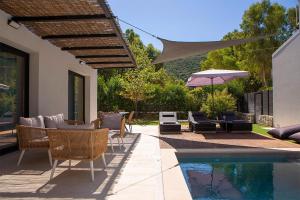 a patio with chairs and an umbrella next to a pool at SEASCAPE VILLAS VASSILIKI - Beachfront villas in Vasiliki