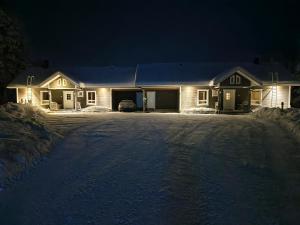 a house in the snow at night at Hietavilla Aurora - Hot tube - Sauna - AC - Fireplace - 11kW EV-refuel - Landscape view - Silence - Free WiFi in Ruka