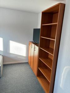 a room with a wooden book shelf with a television at Freundliche Monteurwohnung in Bad Oldesloe