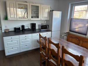 a kitchen with white cabinets and a table and a refrigerator at Freundliche Monteurwohnung in Bad Oldesloe