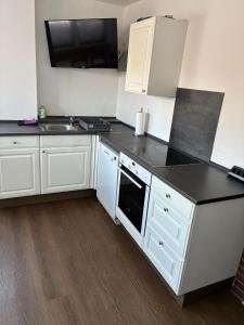 a kitchen with white cabinets and a black counter top at Freundliche Monteurwohnung in Bad Oldesloe +11 photos