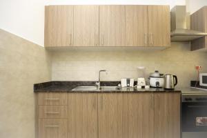 a kitchen with wooden cabinets and a sink at The Empire Tower in Manama +5 photos