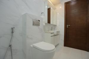 a white bathroom with a toilet and a sink at The Empire Tower in Manama