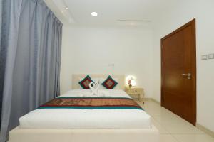 a bedroom with a large white bed with blue curtains at The Empire Tower in Manama