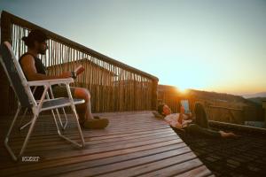 two people sitting on a deck watching the sunset at Chalés VerdeSer in Sêrro
