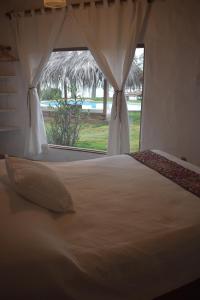a bedroom with a large white bed with a window at Refugio Alana Máncora in Máncora