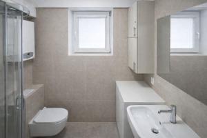 a white bathroom with a toilet and a sink at Apartment Katamaran in Krakow