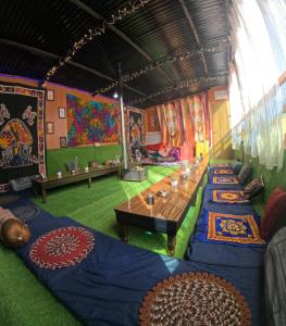a room with a long table in a room with paintings at Kasol Shalom Camps & Cafe in Kasol