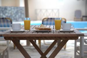 ein Holztisch mit zwei Gläsern Orangensaft und Toast in der Unterkunft Villa Kalamia Dolphin in Perissa