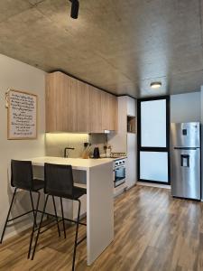 a kitchen with a white counter and two chairs at Canela Loft Rosario in Rosario