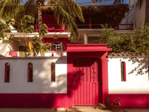 a red and white building with a red door at Casa Porta Rosa in Brisas de Zicatela +16 photos