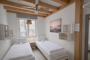two beds in a room with white walls and wooden ceilings at Hamburg Sleep Club in Hamburg