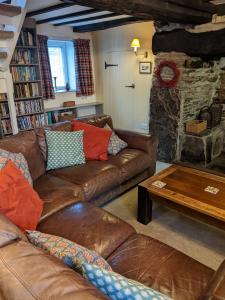 ein Wohnzimmer mit Ledersofas und einem Steinkamin in der Unterkunft Welsh Hideaways in Pentre-briwnant