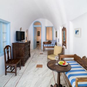 a living room with a tv and a table at Aigialos Luxury Traditional Settlement in Fira