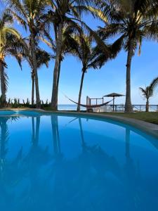 a swimming pool with palm trees in the background at Refugio Alana Máncora in Máncora