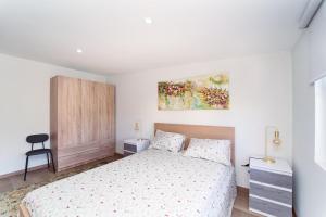 a white bedroom with a bed and a chair at Refúgio do Pilar in Vila Nova de Gaia