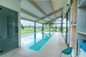 an indoor swimming pool in a house with glass walls at Oase 41 - 5 STAR location with Indoor swimming pool & unique landscape view in Sint-Laureins