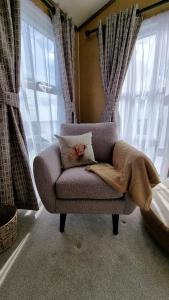 a couch with a blanket on it in a room with windows at 1 Sunset View in Millom