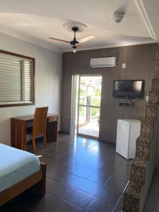 a bedroom with a bed and a desk and a television at Garden Hotel in Nova Era