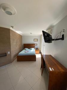 a bedroom with a bed and a desk in it at Garden Hotel in Nova Era